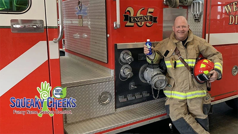 Rock Toone, founder of Squeaky Cheeks, holding Squeaky Cheeks powder by a fire truck